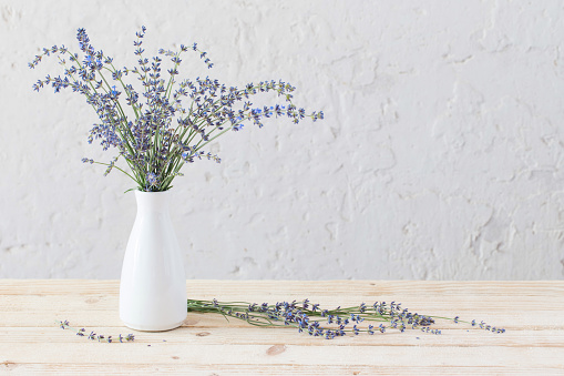 lavender in white vase on wooden table