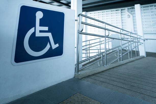 concret forma de rampa com corrimão de aço inoxidável com sinal deficiente para pessoas de cadeira de rodas desabilitada de apoio. - acessibilidade - fotografias e filmes do acervo
