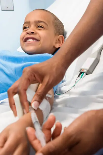 African boy receiving IV medication in hospital bed
