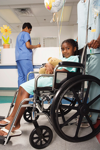 African girl being pushed in wheelchair in hospital