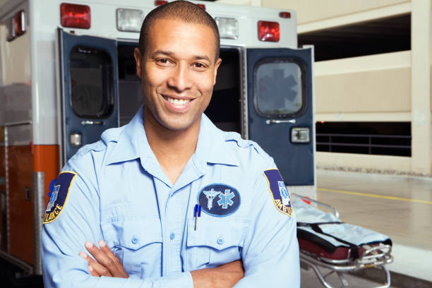 retrato de paramédico africano macho delante de ambulancia - técnico en urgencias médicas fotografías e imágenes de stock