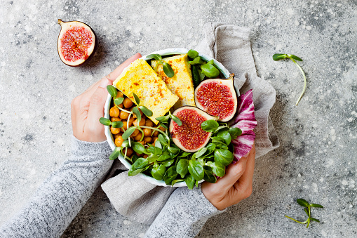 Vegan, detox Buddha bowl recipe with turmeric roasted tofu, figs, chickpeas and greens. Top view, flat lay