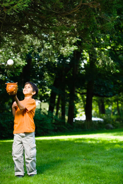 istock Hispanic boy playing with baseball in park 1035100690