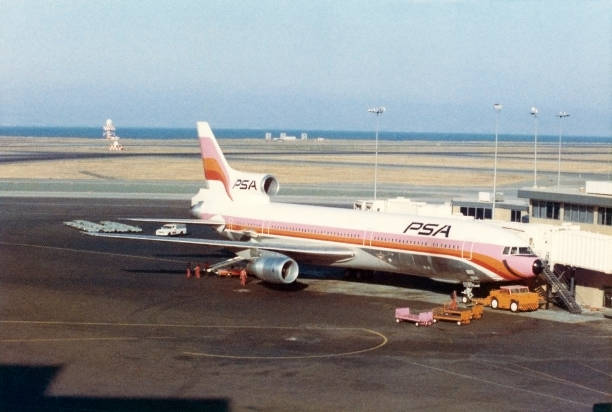 PSA (Pacific Southwest Airlines) Lockheed L-1011 TriStar jet airplane at gate at San Francisco International Airport, California, USA, August 1974. Scanned film with grain.