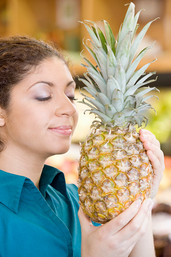 Mixed Race woman smelling pineapple