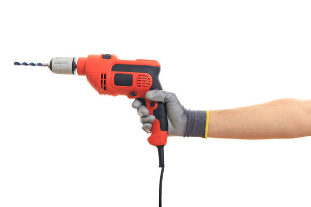 Gloved hand holding an orange electric drill on white background