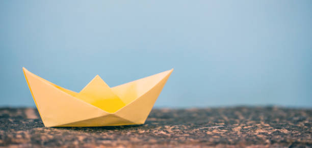 istock Yellow paper folded, origami, boat on blue background 1035112482