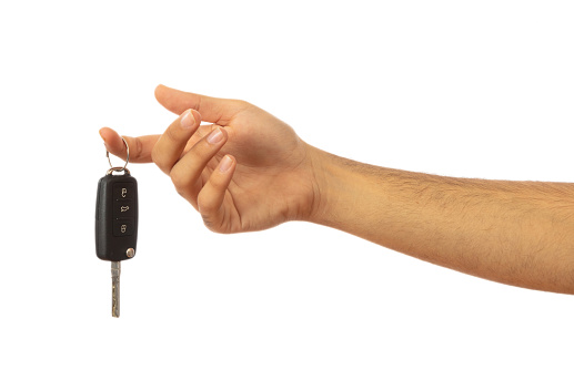 Male hand holding a car key isolated on white background, clipping path