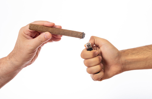Smoking. Cuban cigar in a male hand and lighter in another hand isolated on white background, clipping path