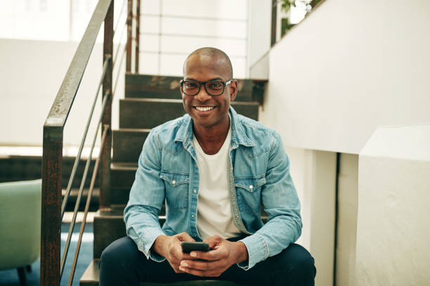 istock Smiling African businessman reading texts on office stairs 1035114368
