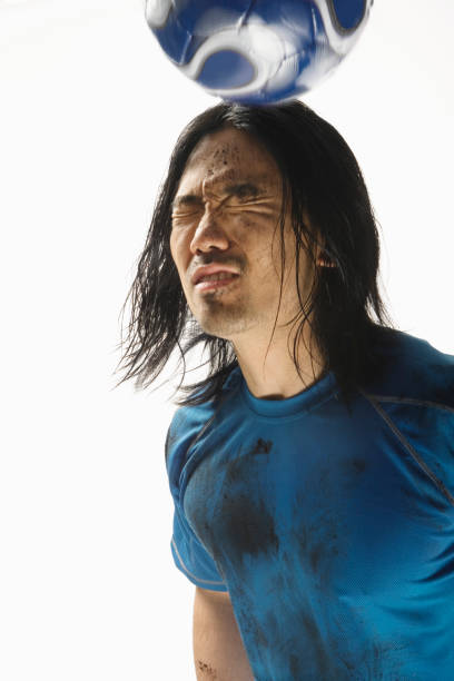 istock Asian male soccer player bouncing ball on head 1035121090