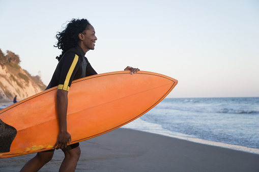 African woman carrying surfboard