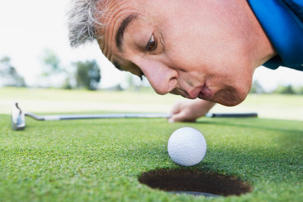 uomo che soffia sulla pallina da golf - golf putting determination focus foto e immagini stock