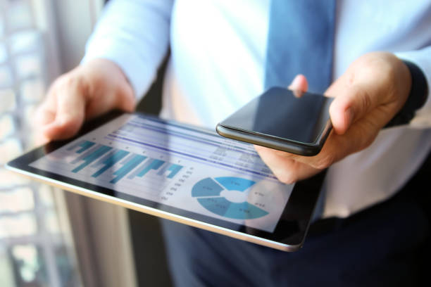 istock Business man working and analyzing financial figures on a graphs on a tablet and mobile phone 1035135862