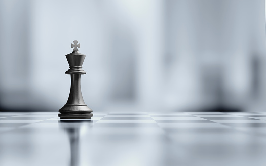 Single king chess piece is standing on black and white chessboard. Horizontal composition with selective focus and copy space. Great use for strategy concepts.