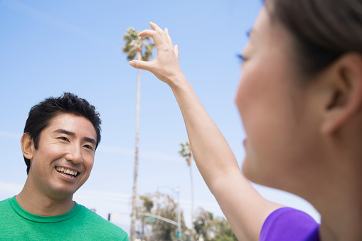 Asian woman holding fingers up to palm tree