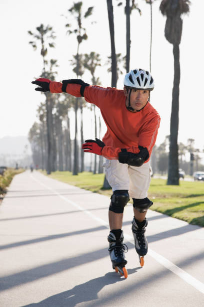 rollerblading uomo asiatico - pattinaggio in linea foto e immagini stock