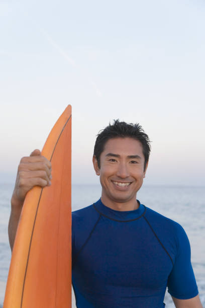 istock Asian man holding surfboard 1035136858