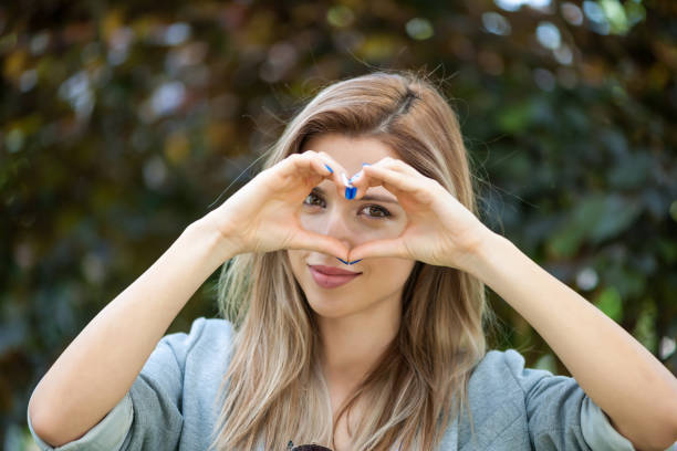 Young woman doing a heart with her hands.
