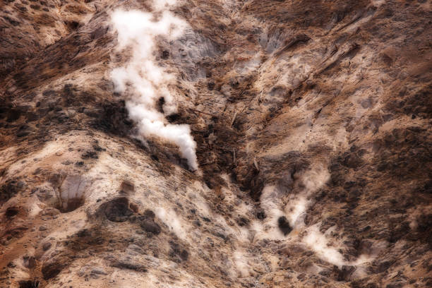 A puff of steam erupting out of a rocky mountainside at yellowstone national park