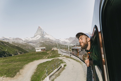 Young Caucasian man looking out of the window on the train near Matterhorn