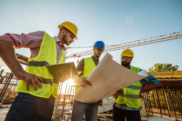 istock Architects and engineers looking at blueprint near crane 1035156912