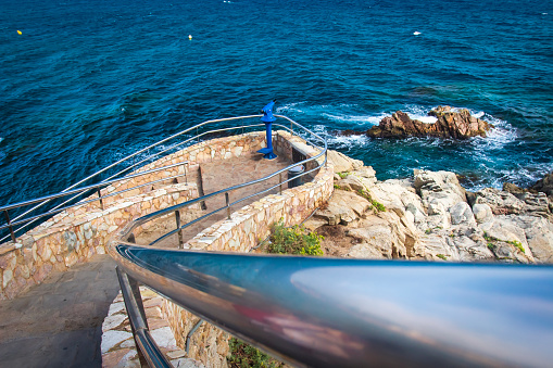 Stone staircase to the observation deck with a telescope in Lloret de Mar, Costa Brava, Spain. Viewpoint on rocky coastline in Lloret. Famous spanish place in Lloret de Mar.