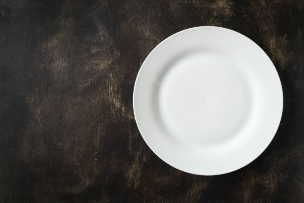 istock White empty plate on a black background. Free space for an inscription. 1035162614