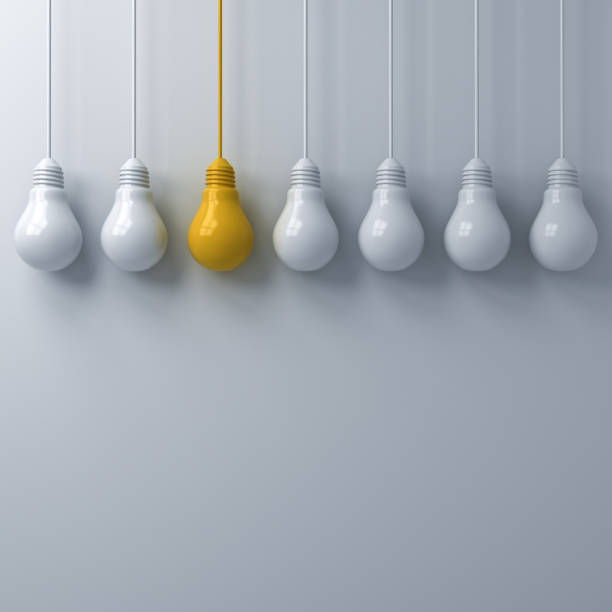 istock Think different concept One hanging yellow light bulb standing out from the white light bulbs on white wall background with shadows leadership and individuality creative idea concepts 3D rendering 1035163240