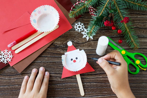 The child draws details Christmas Santa stics puppets. Handmade. Project of children's creativity, handicrafts, crafts for kids. The child draws details Christmas Santa stics puppets. Handmade. Project of children's creativity, handicrafts, crafts for kids. animal arm photos stock pictures, royalty-free photos & images
