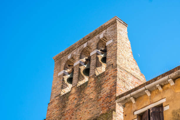 red brick bell tower with three metal bells in Venice, Italy.