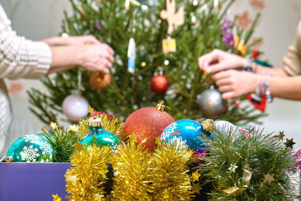 gens de décorer un arbre de noël avec des boules de noël à moscou plat - christmas ball christmas ornament human hand photos et images de collection