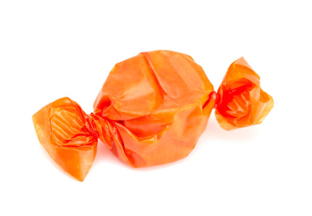 naranja envuelta caramelos sobre un fondo blanco - taffy fotografías e imágenes de stock