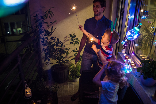 A father and his children, a boy and a girl are decorating their terrace for Christmas Eve. It's tropical climate, and it's hot weather outdoor.