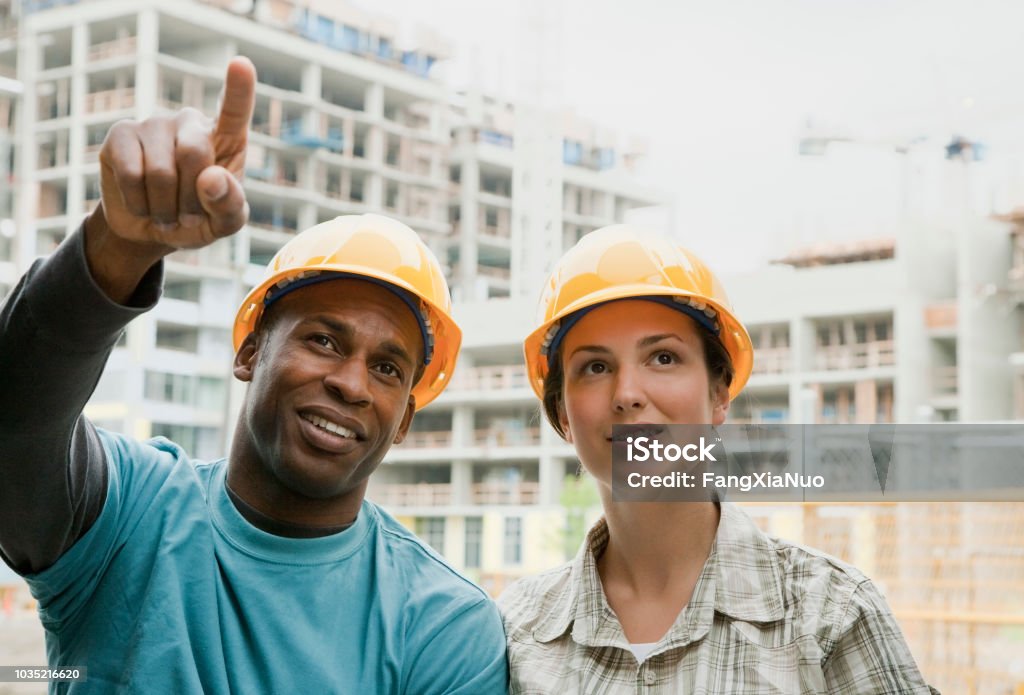 Man and woman in hard-hats on construction site Construction Site Stock Photo