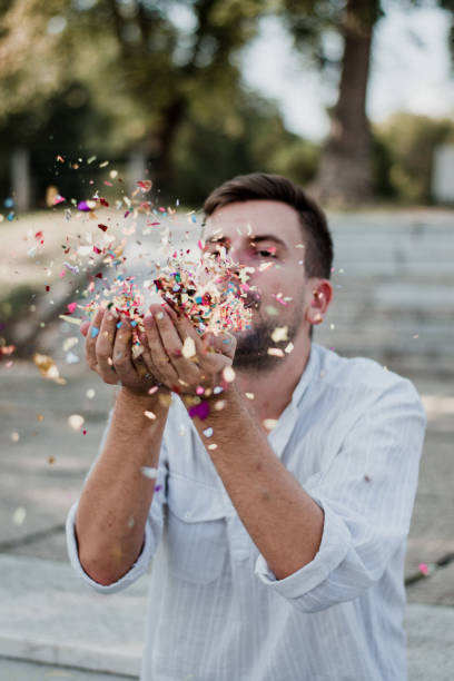 istock Portrait Of Young Man Blowing Confetti 1035219424