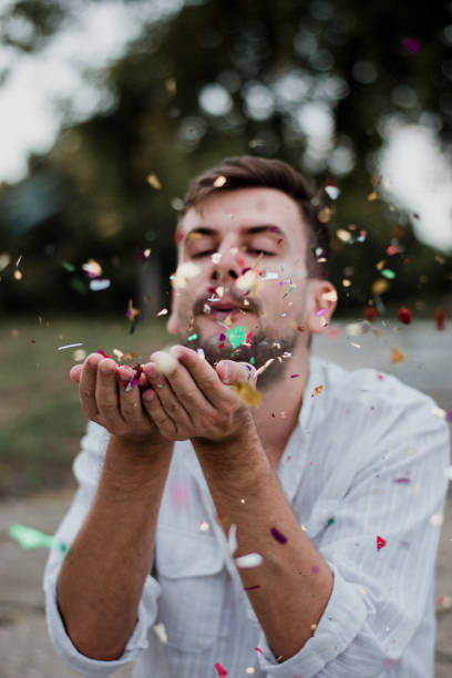 istock Portrait Of Young Man Blowing Confetti 1035219438