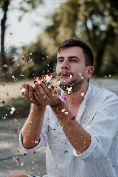istock Portrait Of Young Man Blowing Confetti 1035219454