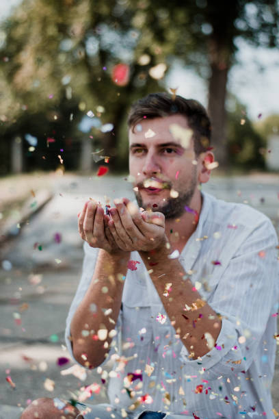 istock Portrait Of Young Man Blowing Confetti 1035219458