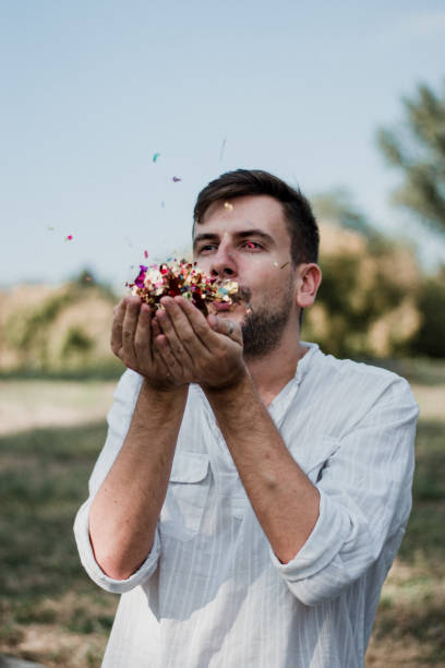istock Portrait Of Young Man Blowing Confetti 1035219480