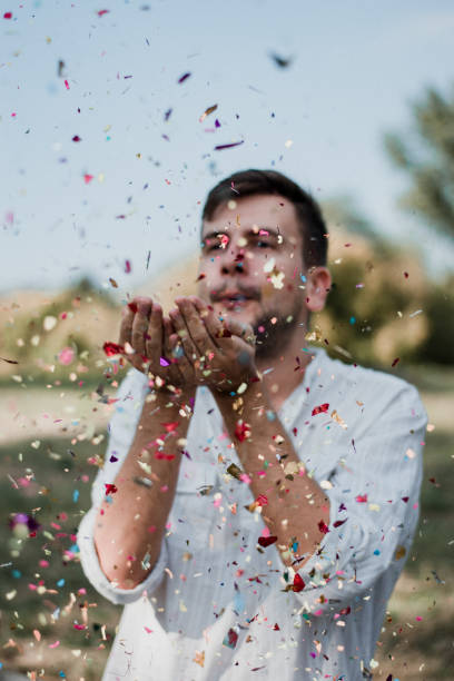 istock Portrait Of Young Man Blowing Confetti 1035219490