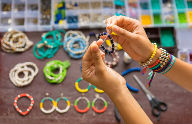 weibliche hände machen handgefertigte bijouterie mit kleinen bällen und steinen - costume jewelry stock-fotos und bilder