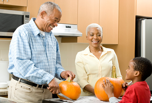 African grandparents carving pumpkins with grandson