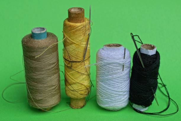 istock a row of bobbins with colored threads and needles on a green table 1035229580