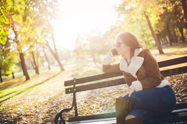 istock Young woman talking on phone in a park 1035232180