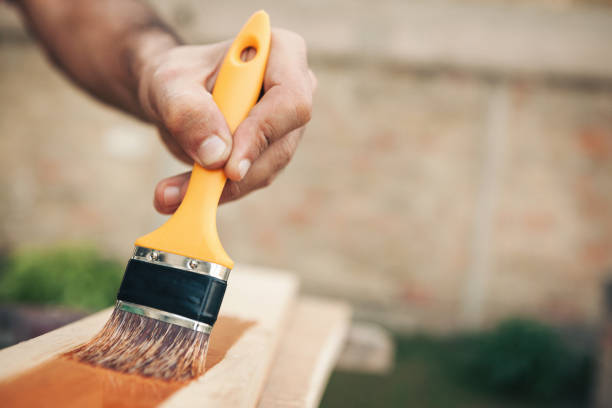 Young man painting and fixing wooden board