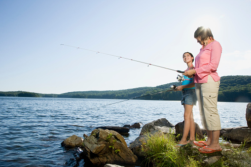 Learning to fishing. Father and mother with son and daughter together outdoors at summertime.