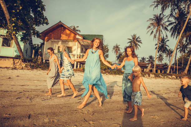 Friends playing in waves on beach Friends running into waves on beach family beach vacations travel stock pictures, royalty-free photos & images