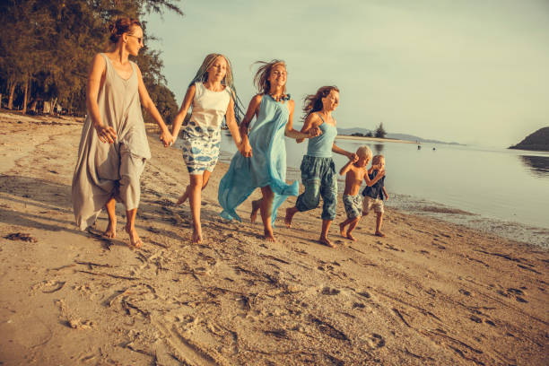 Friends playing in waves on beach Friends running into waves on beach family beach vacations travel stock pictures, royalty-free photos & images