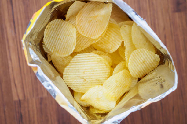 istock Potato chips in open snack bag close up on table floor 1035264820